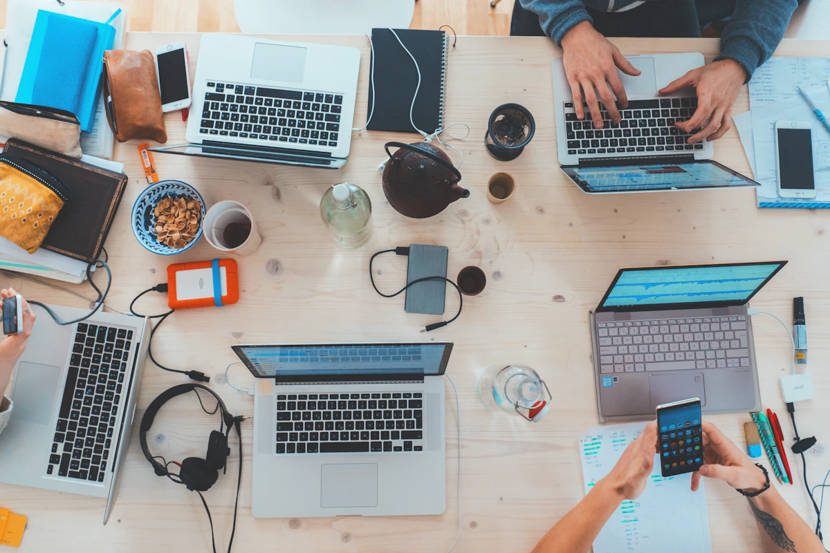 An overhead view of a shared table with laptops and notebooks